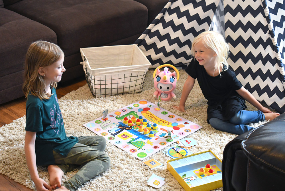 girls playing board game with robot toy